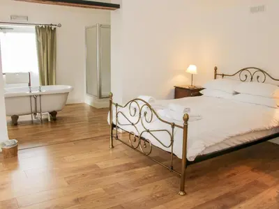 a bedroom with a bed and a bathtub and a bath tub at Stockbatch Granary at Pitchford Estate in Shrewsbury