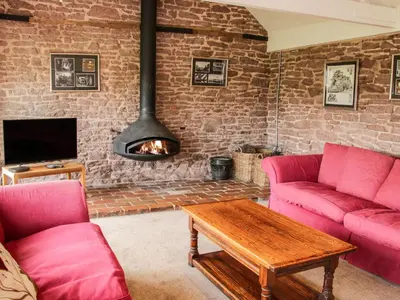 a living room with two pink couches and a fireplace at Stockbatch Granary at Pitchford Estate in Shrewsbury