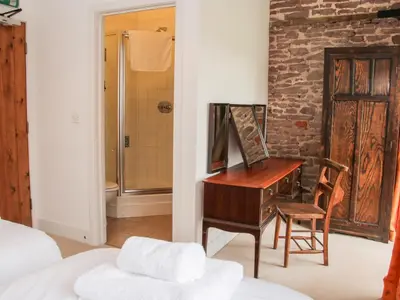 a bedroom with a desk and a bathroom with a shower at Stockbatch Granary at Pitchford Estate in Shrewsbury