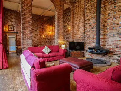a living room with red furniture and a brick wall at Windy Mundy Farm at Pitchford Estate in Shrewsbury