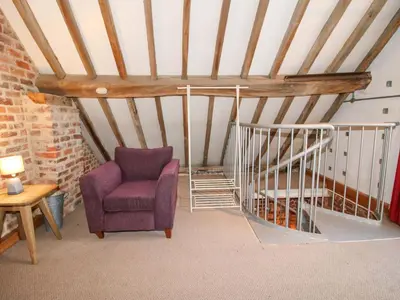 a attic room with a chair and a staircase at Windy Mundy Farm at Pitchford Estate in Shrewsbury