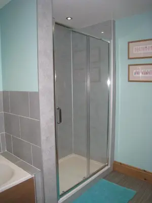 a shower with a glass door in a bathroom at Bryn Derw in Talsarnau