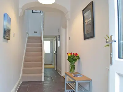 a hallway with stairs and a vase of flowers on a table at Bristol House in New Quay