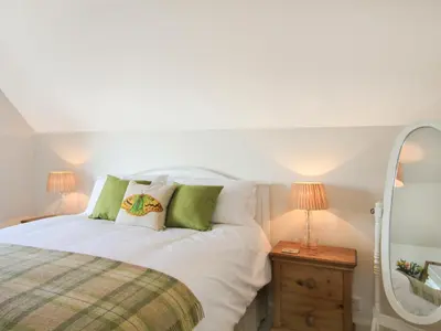 a bedroom with a white bed and a mirror at Garnedd Lwyd in Harlech