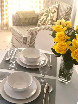 a table with plates and a vase of yellow roses at Wisteria Cottages are self catering cottages in a beautiful village location in Dorrington