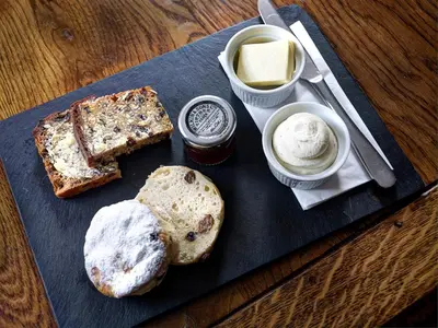 a black plate with bread and butter and other foods at Brigands Inn in Mallwyd