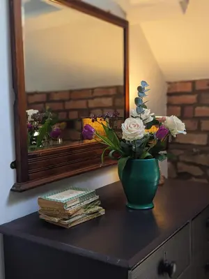 a vase of flowers on a table in front of a mirror at Little Underhill in Oswestry