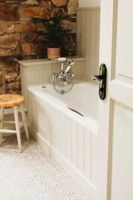 a bath tub in a bathroom with a chair and a plant at Little Underhill in Oswestry