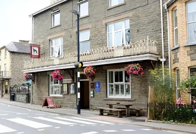 a building on a street with a bench in front of it at Greyhound Hotel in Wales