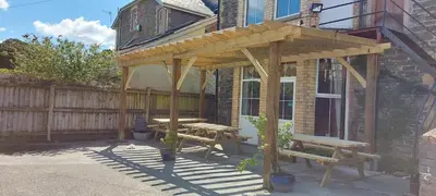 a wooden pergola with a picnic table and a bench at Greyhound Hotel in Wales