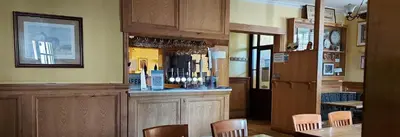 a restaurant with a bar with wooden cabinets and chairs at Greyhound Hotel in Wales