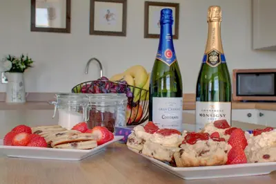 a table with two bottles of wine and strawberries at 3 Bed in Welshpool oc-bow122 in Welshpool