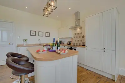 a kitchen with white cabinets and a counter with a stool at 3 Bed in Welshpool oc-bow122 in Welshpool