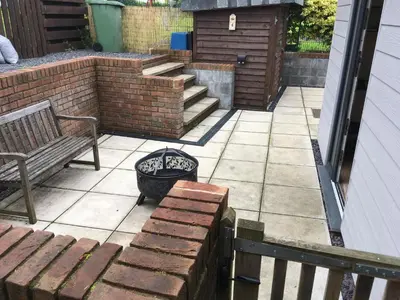 a patio with a bench and a basket and stairs at 1 Rhys Terrace in Pennal