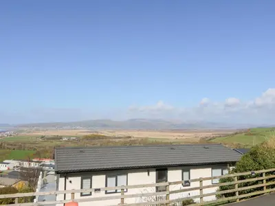 a white house with a black roof on a hill at McAuliffe Lodge in Borth