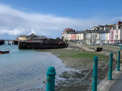 a body of water with houses and a pier at Driftwood in Aberdyfi