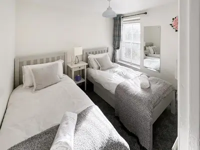 a bedroom with two beds and a mirror at Driftwood in Aberdyfi