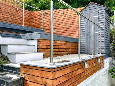 a garden with a wooden retaining wall and stairs at Driftwood in Aberdyfi