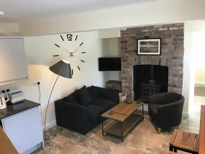 a living room with a couch and a clock on the wall at Bettws Hall Accommodation in Newtown