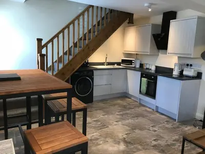 a kitchen with white cabinets and a staircase with a table at Bettws Hall Accommodation in Newtown