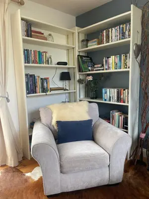 a couch in a living room with bookshelves at Archers Cottage in Leominster