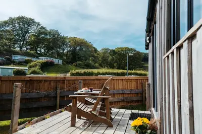 a wooden chair sitting on a deck with a table at Cefn Crib Cabins in Machynlleth
