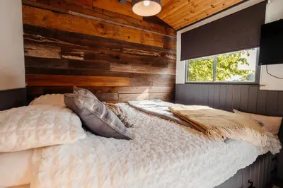 a bedroom with a bed with a wooden wall at Cefn Crib Cabins in Machynlleth