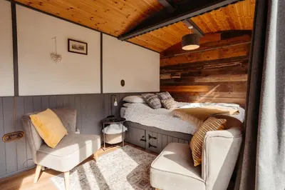 a bedroom with a bed and a chair in a room at Cefn Crib Cabins in Machynlleth