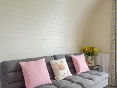 a gray couch with pink and white pillows on it at Cain Pod Vip in Llanfyllin