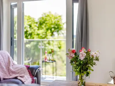 a vase of flowers on a table in front of a window at Barn Owls Rest in Clyro