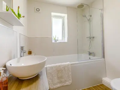 a white bathroom with a tub and a sink at Barn Owls Rest in Clyro