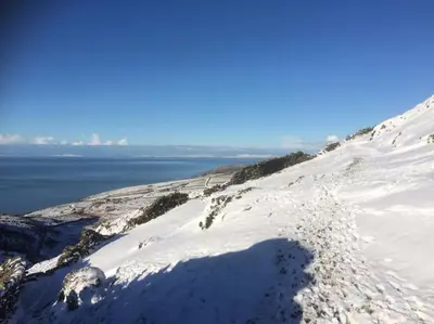 a snow covered hill with a view of the water at Cwt y Bugail in Barmouth