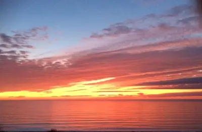 a sunset over a body of water with the sky at Cwt y Bugail in Barmouth
