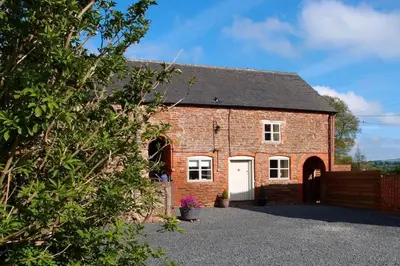 a red brick building with a white garage at Upper Heath Farm - Stable Cottage Ludlow in Craven Arms