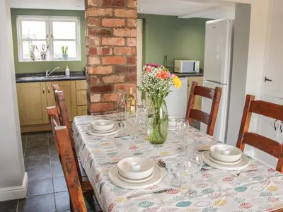 a dining room table with a vase of flowers on it at 1 Royal Oak Cottages in Shrewsbury
