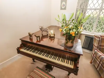 a piano with a vase of flowers on a table at Top Farm House in Oswestry
