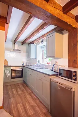a kitchen with white cabinets and a wooden floor at Lower House B&B and Cottages, Adforton in Leintwardine