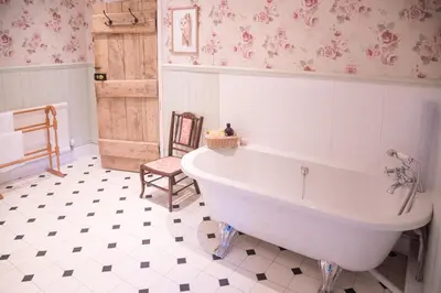 a bathroom with a large white tub and a chair at Lower House B&B and Cottages, Adforton in Leintwardine