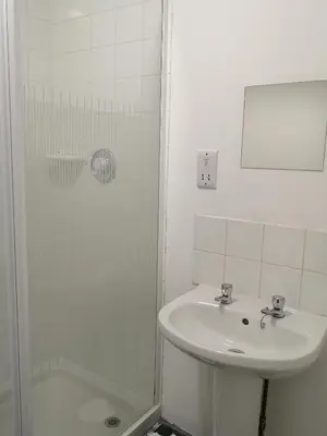 a white bathroom with a sink and a shower at Ty'r Bont Studios in Newtown