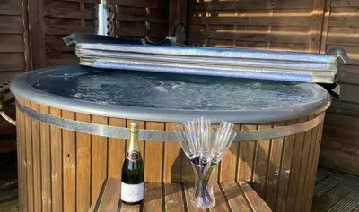a hot tub with a bottle of wine and a glass at The old school house in Burwarton