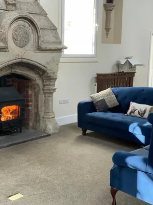 a living room with a blue couch and a fireplace at The old school house in Burwarton