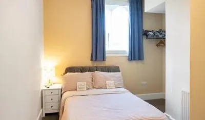 a bedroom with a bed with blue curtains and a window at The old school house in Burwarton