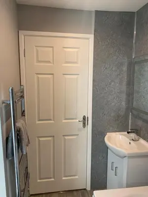 a bathroom with a white door next to a sink at 6 Tai Isa, A Hidden Gem in Barmouth