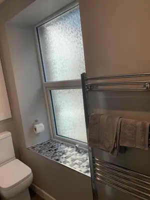 a bathroom with a shower with a window and a toilet at 6 Tai Isa, A Hidden Gem in Barmouth