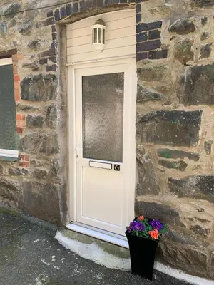 a door with a flower pot in front of a stone wall at 6 Tai Isa, A Hidden Gem in Barmouth