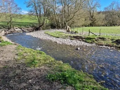a stream of water with rocks in a field at Riverside Cabin - Sleeps 2 - HotTub - Parking in Oswestry