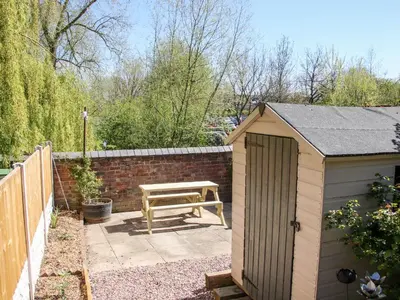 a wooden bench and a picnic table in a garden at Willow View in Shrewsbury