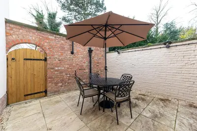 a table and chairs with an umbrella on a patio at Coach House, Shrewsbury Town in Shrewsbury