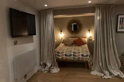 a bedroom with a bed with curtains and a television at Wilderness Lodge in Oswestry