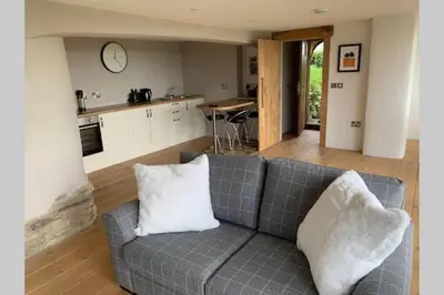 a living room with a couch and a kitchen at Wilderness Lodge in Oswestry